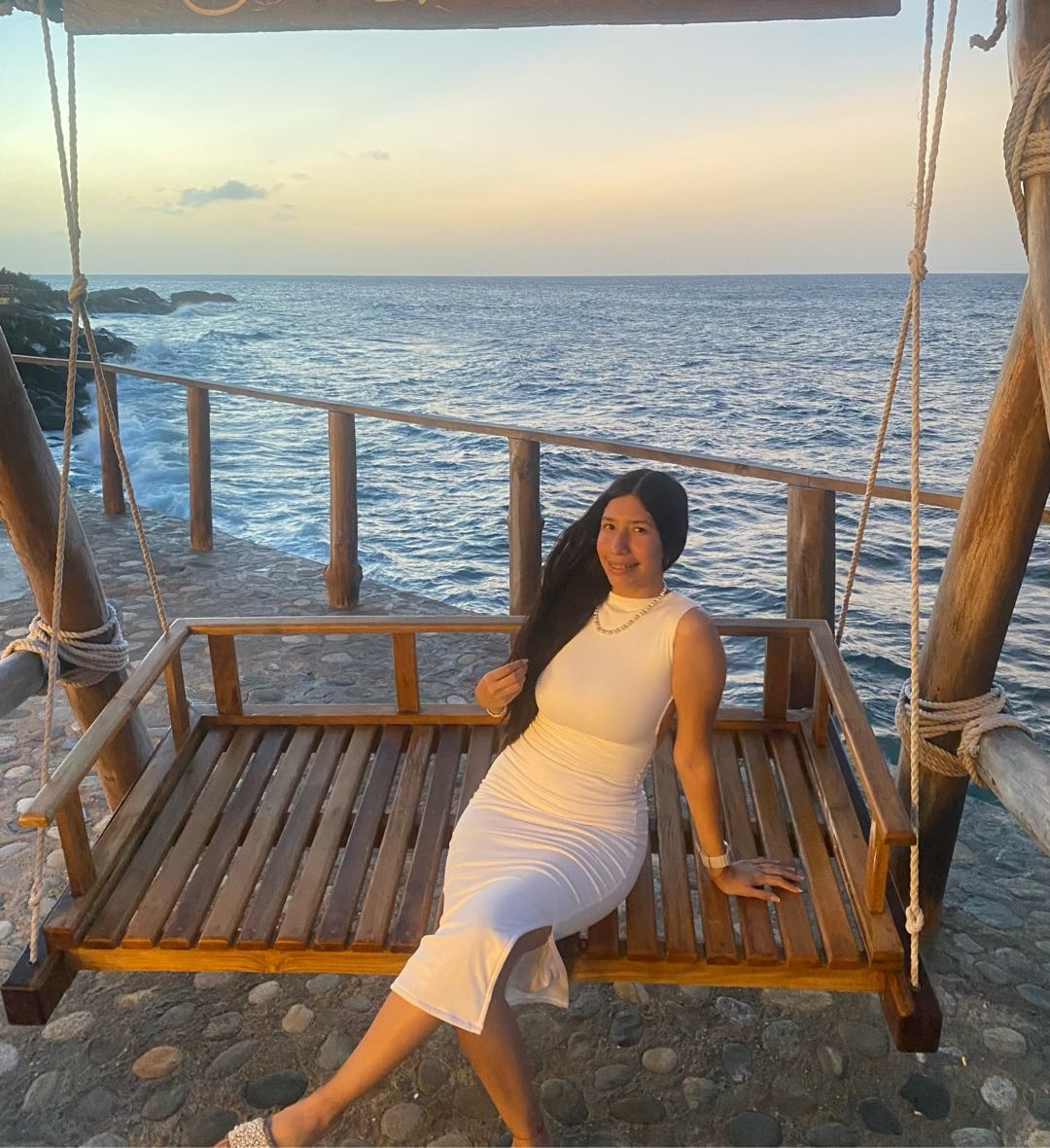 Woman in a white dress beside the sea at sunset