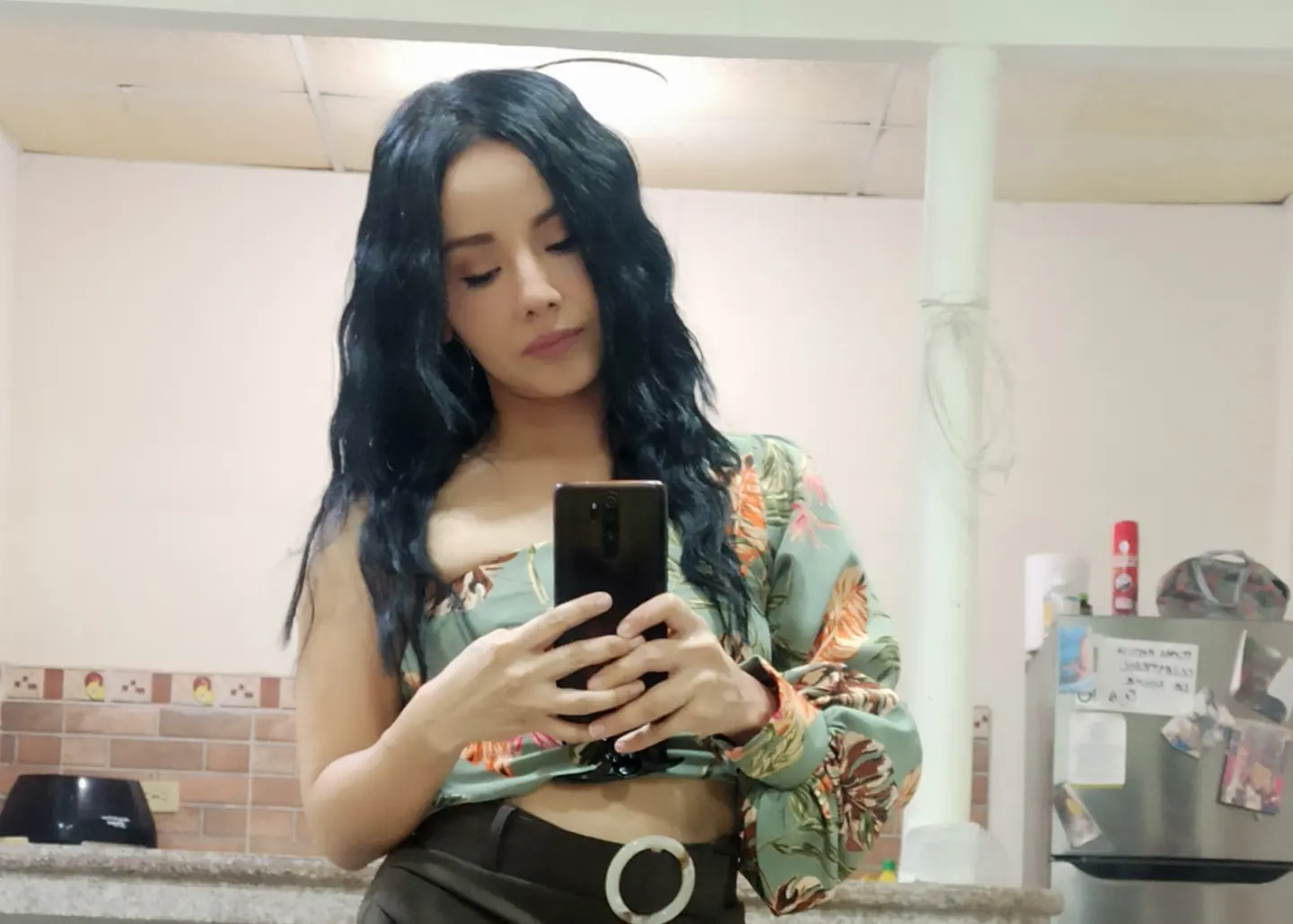Woman with wavy dark hair wearing a green floral top